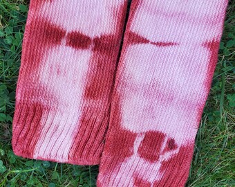 May include: A pair of red and white tie-dye socks with a checkered pattern. The socks are made of a soft, knitted fabric.