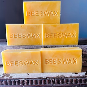 May include: Four rectangular blocks of beeswax, stacked in a pyramid shape. Each block is labelled "BEESWAX".
