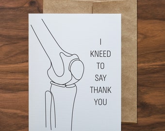 May include: A white card with a black line drawing of a knee joint. The text on the card reads "I kneed to say thank you".