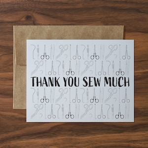 May include: A white card with a black and white illustration of sewing tools and the text "THANK YOU SEW MUCH".