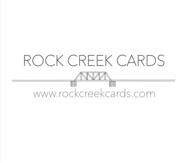 Puede incluir: Logotipo minimalista de Rock Creek Cards con el texto "ROCK CREEK CARDS" en una fuente limpia y sin serifa. Debajo, un gr&aacute;fico de puente estilizado y la direcci&oacute;n web www.rockcreekcards.com.