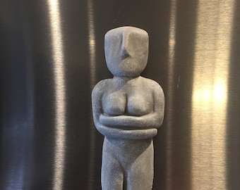 May include: A gray, stylized sculpture of a person with arms crossed over their chest. The sculpture is made of a rough, textured material.