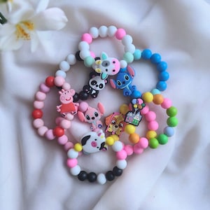May include: A set of colourful silicone bracelets with various cartoon character charms, including a pig, a dog, a panda, and a house. The bracelets are made of soft, flexible silicone and are perfect for children.