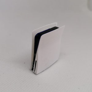 May include: A white gaming console with a black top and a blue accent. The console is standing upright on a white surface.