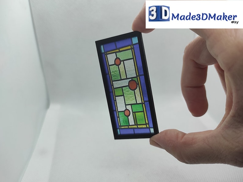 May include: A stained glass window with a black frame. The glass is green, blue, and yellow with red circles. The window is about 4 inches tall.