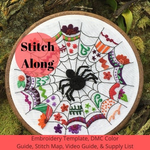 May include: Embroidered hoop art featuring a black spider in a web with colorful flowers and geometric patterns. The hoop has a wooden frame and the text "Stitch Along" is written in red on a pink circle.