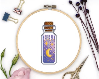 Peut inclure: Un motif de point de croix représentant une bouteille en verre avec un bouchon en liège remplie d'un liquide violet et des étoiles jaunes et une lune croissante.