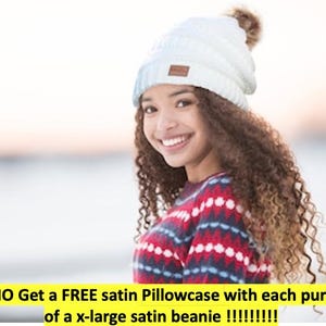 May include: A white ribbed knit beanie featuring a brown faux fur pom-pom and a small rectangular brown leather-effect patch on the front. The text at the bottom reads: PROMO Get a FREE satin Pillowcase with each purchase of a x-large satin beanie !!!!!!!!!