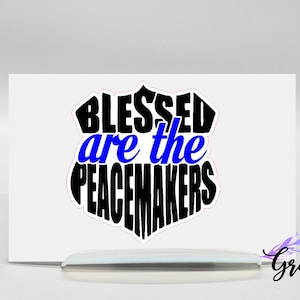 May include: A white card with a black and blue graphic that says "Blessed are the Peacemakers".