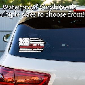 May include: A white car's rear window displays a distressed American flag vinyl decal. The decal features a red stripe, white stars, and stripes, with the word "wife" in red script. Text above reads "Waterproof Vinyl Decals Multiple sizes to choose from!"