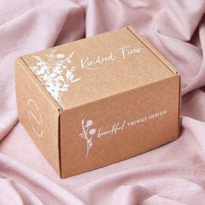 May include: A brown cardboard box with white floral designs and the text "Kindred Fires" and "beautiful things inside".