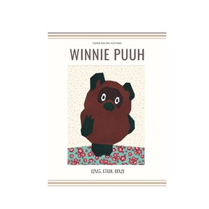Könnte beinhalten: Papier-Patchwork-Muster für Winnie Puuh, einen braunen Bären mit schwarzen Augen und Nase, der auf einem blau-weiß gemusterten Stoff steht. Das Muster umfasst die Größen 12x15, 15x18 und 18x21 Zoll.