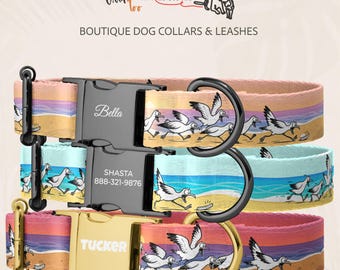 May include: Three dog collars featuring a beach scene with cartoon seagulls. The top collar has a black buckle with the name Bella. The middle collar has a black buckle with Shasta and 888-321-9876. The bottom collar has a gold buckle with Tucker.