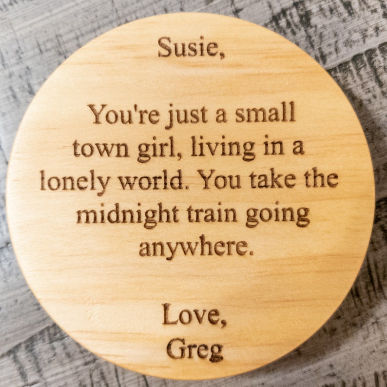 May include: A wooden coaster with a laser-engraved message that reads: "Susie, You're just a small town girl, living in a lonely world. You take the midnight train going anywhere. Love, Greg".