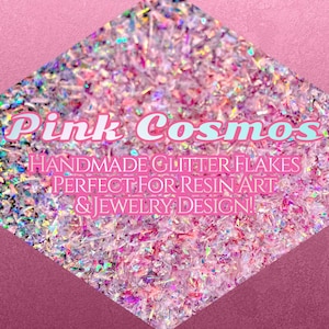 May include: Pink Cosmos handmade glitter flakes in a diamond shape. The glitter is a mix of pink, silver, and iridescent colors. Text on the image reads "Handmade Glitter Flakes Perfect for Resin Art & Jewelry Design!"