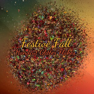 May include: A close-up of festive fall handcut glitter flakes. The glitter is a mix of red, gold, green, and iridescent colors.