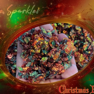 May include: A close-up of iridescent red, green, and gold glitter flakes. The glitter is labeled "Fire Sparkles Christmas Blend".