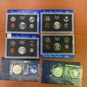 May include: Several United States Proof Sets from 1968, 1970, and 1973. Each set includes various coins in protective cases. The sets are in blue boxes with the text "United States Proof Set" and the year printed on them.