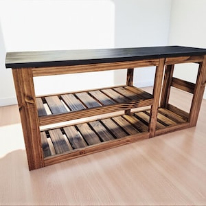 Op de afbeelding: Een houten console met een donker gebeitst blad en twee onderste planken. De tafel is gemaakt van gebeitst hout, met de natuurlijke nerf. De planken zijn voorzien van lamellen en de tafel is ongeveer 152 cm lang.