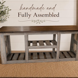 May include: A handmade, fully assembled wooden bench with a dark brown top and gray-painted base. The bench has two open shelves and is displayed on a woven rug. The text "handmade and Fully Assembled" is above the bench.