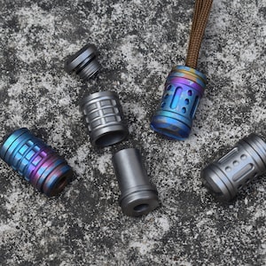 May include: Five different titanium fidget toys in various colours and designs. The toys are cylindrical and have different patterns and textures. They are all made of metal and have a shiny finish.