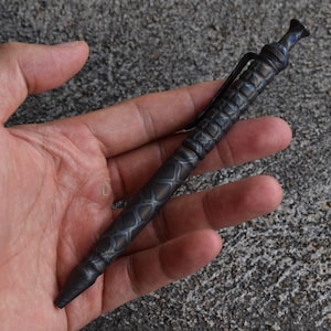 May include: A black and blue titanium pen with a textured pattern. The pen is closed and has a clip.