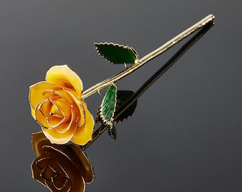 May include: A single golden rose with yellow petals and green leaves. The rose is on a black background.