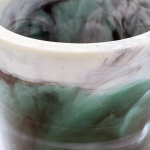 Puede incluir: Primer plano de una maceta de cerámica marmoleada en verde, blanco y marrón. La maceta tiene un borde blanco liso.