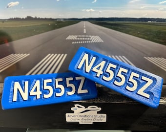 May include: Two rectangular blue airplane wheel chocks featuring the white embossed registration number N4555Z. The chocks are positioned in front of a printed image of an airport runway, with a small label reading 4ever Creations Studio.