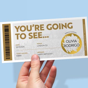 May include: A rectangular event ticket featuring gold text that reads YOU'RE GOING TO SEE... with a scratch-to-reveal gold circular panel displaying the name OLIVIA RODRIGO. The ticket includes fields for date 26/11/2026, venue LONDON O2, and ticket holder EMMA.