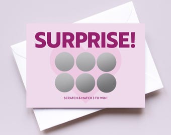 Pode incluir: Um cartão rosa e roxo com a palavra "SURPRISE!" em letras roxas em negrito. O cartão tem seis círculos prateados para riscar dispostos em forma de coração. O texto "SCRATCH & MATCH 3 TO WIN!" está impresso abaixo dos círculos.