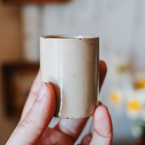 May include: A set of three ceramic mugs with a speckled, matte finish. The mugs are in shades of cream, light gray, and dark gray. Each mug has a simple, minimalist design and a rounded handle.