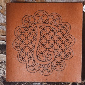 May include: A brown card with a black and white design of a letter T surrounded by a circular pattern of overlapping circles.