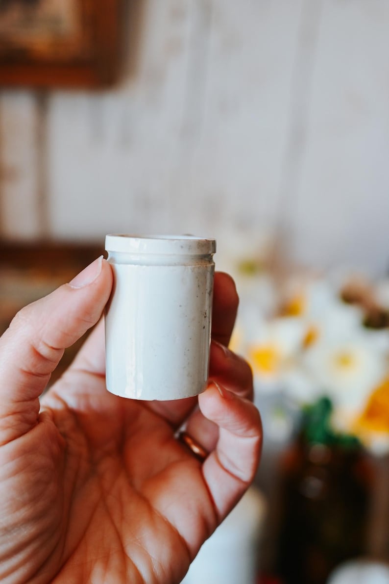 May include: A white ceramic mug with a black handle and the text "But First, Coffee" in a black, bold font. The mug is sitting on a wooden surface. The mug is 4 inches tall.