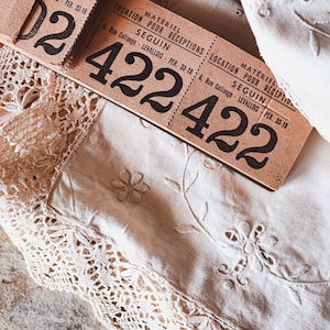 May include: Close-up of two vintage brown paper tickets with the text "Matériel pour Réceptions Location pour Réceptions Seguin 6, Rue Collange Levallois - Per. 33-18" and the number "422" printed on each ticket.