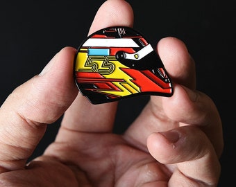 May include: A black, red, and yellow racing helmet pin with the number "55" on the side.