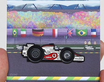 May include: A white and red Formula One race car pin with black wheels and the Vodafone logo. The pin is on a card with a colorful confetti background and the text "The Geekly Forge".