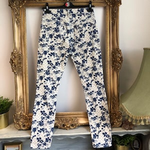 May include: White skinny jeans with a blue floral pattern.