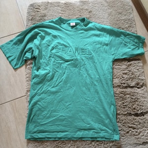 Può includere: Una maglietta verde acqua con la scritta "CHANEL" in rilievo sul davanti.