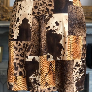 May include: A brown and beige mini skirt with a patchwork design featuring animal prints, including leopard, snake, and cowhide.