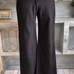 Könnte beinhalten: Schwarze weite Hose mit Knopfverschluss und gerader Passform.