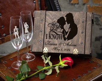 Può includere: Una scatola di legno con un coperchio incernierato, incisa con una silhouette di una coppia e il testo "I love you I KNOW", "Faina & Adam" e "May 3, 2024". Due flute da champagne con silhouette incise di personaggi di Star Wars sono davanti alla scatola.