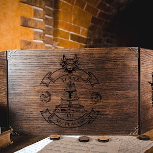 May include: A wooden tabletop gaming screen with a dragon design and the text "TEARS OF MY PLAYERS". The screen is made of dark wood and has metal corner accents. Dice and a sword are also etched into the wood.