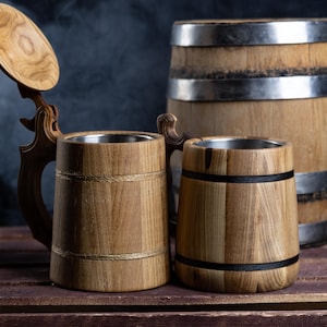 May include: Two wooden beer mugs with metal lids, one with a lid that is open, and a wooden barrel with metal bands.