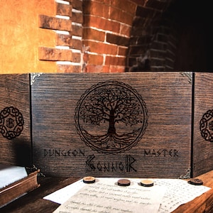 May include: A wooden box with a hinged lid, featuring a tree of life design and the text "Dungeon Master & Guildnik".