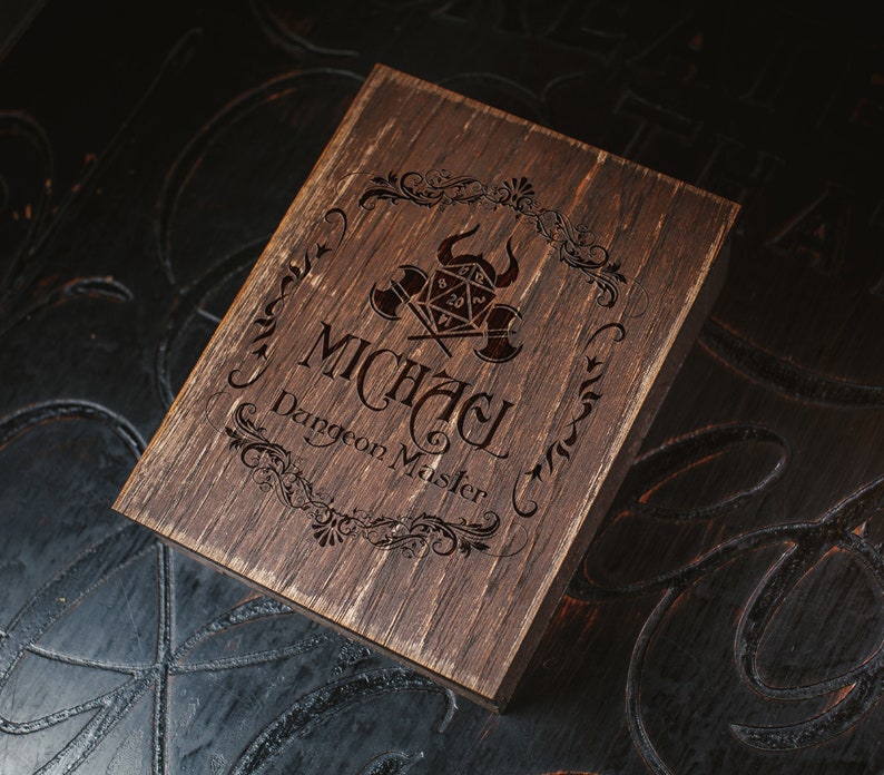 Puede incluir: Una caja de madera marr&oacute;n oscuro con un dise&ntilde;o decorativo y el texto "Michael Dungeon Master" grabado en la parte superior.