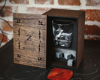 May include: Wooden box with a glass whiskey tumbler, three grey stone ice cubes, and a leather coaster. The glass and coaster are engraved with the letter "Z" and the name "Michael".