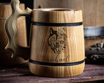 May include: A wooden beer stein with a stainless steel interior. The stein has a black band around the top and bottom and a wolf design with floral accents engraved on the front. The name "michael" is engraved below the design.