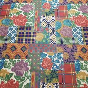 May include: A patchwork textile with a mix of floral and geometric designs. It features large, colourful flowers in red, purple, and yellow, alongside squares of plaid, diamonds, and other shapes, creating a vibrant, patterned surface.