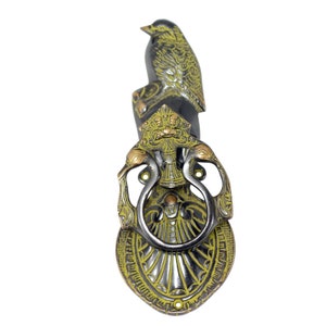 May include: A decorative door knocker with a bird design. The knocker is made of brass and has a black and green finish. The bird is perched on top of a decorative base with a ring for knocking.
